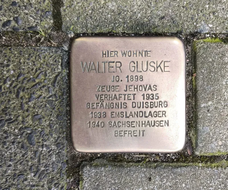Stolperstein mit der Inschrift: "Walter Gluske / Jg. 1898 / Zeuge Jehovas / Verhaftet 1936 / Gefängnis Duisburg / 1938 Emslandlager / 1940 Sachsenhausen / Befreit