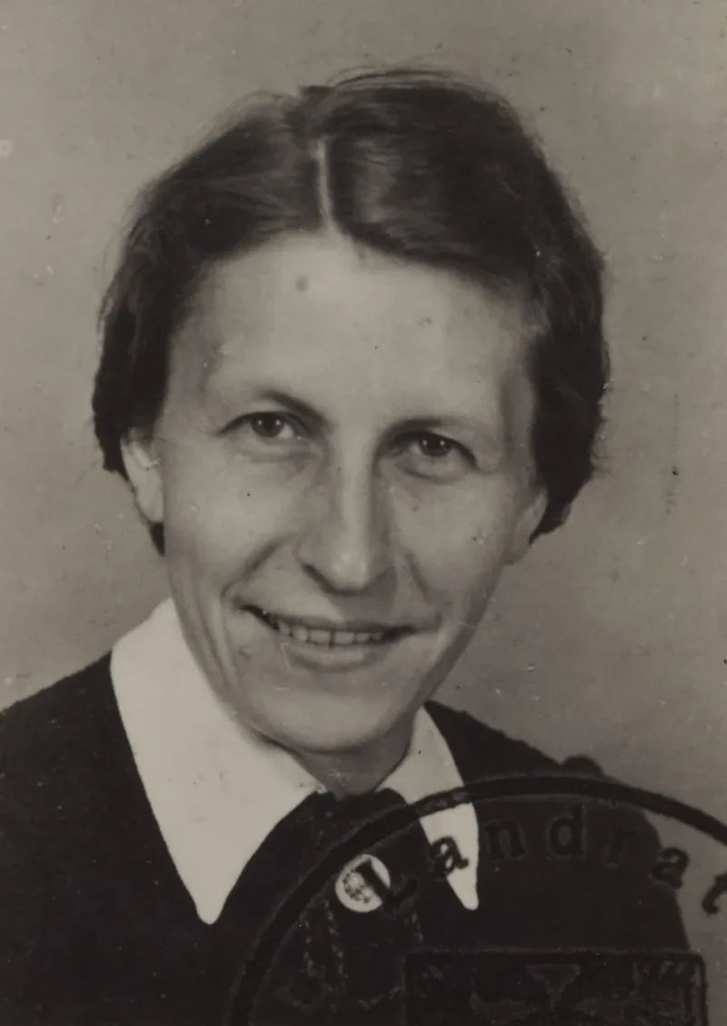 Eine Frau in den 30er/40er Jahren blickt in die Kamera. Auf dem Foto ist ein Stempel, auf dem die Buchstaben "LANDRAT" zu lesen sind.