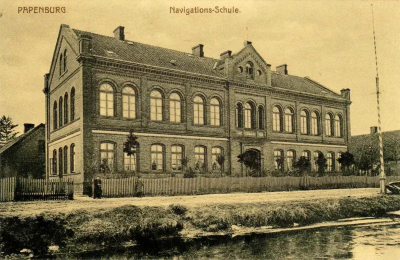 Historische Postkarte eines zweistöckigen Gebäudes mit Satteldach und Rundbogenfenster, sowie eines hervorgehobenen Eingangs.