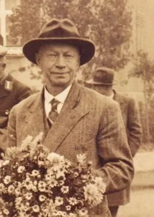 Paul Otto Schneider in einem Anzug mit Hut und einem Strauß Blumen in der Hand