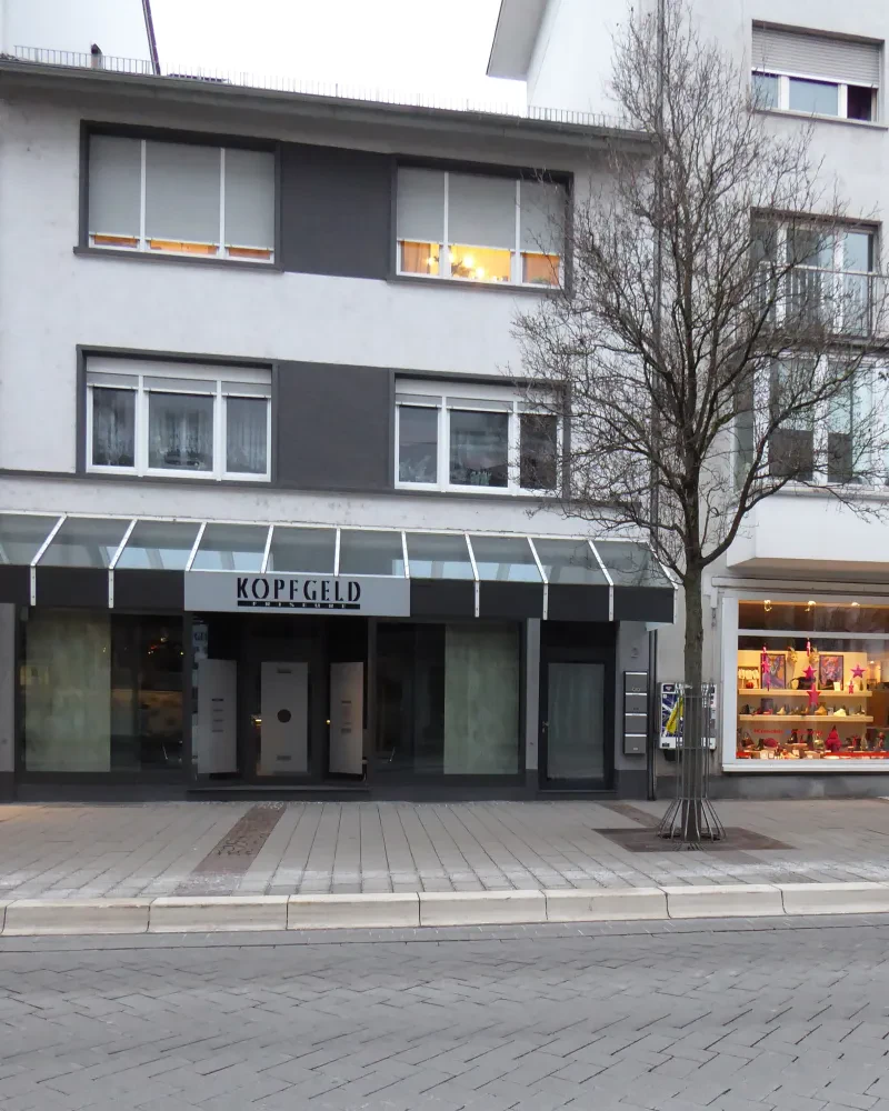 Ein Neubau, unten ein Frisörsalon, über dem Eingang steht "Kopfgeld".