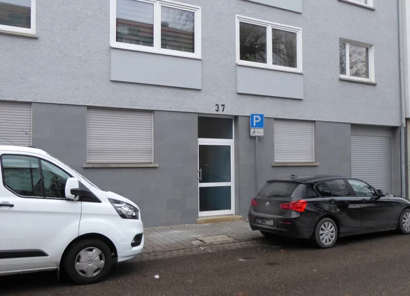 Ein Hauseingang mit der Nummer 37 darüber, davor zwei parkende Autos.