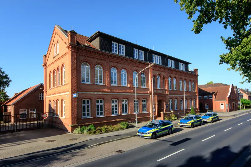 Ein dreistöckiges, rotes Backsteingebäude mit ausgebautem Walmdach.