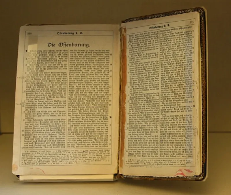 Eine Aufgeschlagene Bibel zeigt das Bibelbuch Offenbarung.