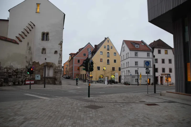 Blick auf einen Platz, ein Radfahrer kommt entgegen, mittig die Gedenkstele für Jehovas Zeugen.