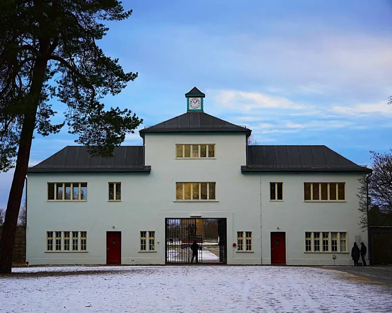 Ein dreistöckiges helles Gebäude mit Uhrenturm und Eisengittertor in der Mitte steht im Schnee.