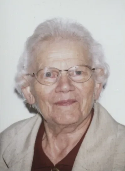 Eine ältere, grauhaarige Dame mit Brille lächelt in die Kamera.