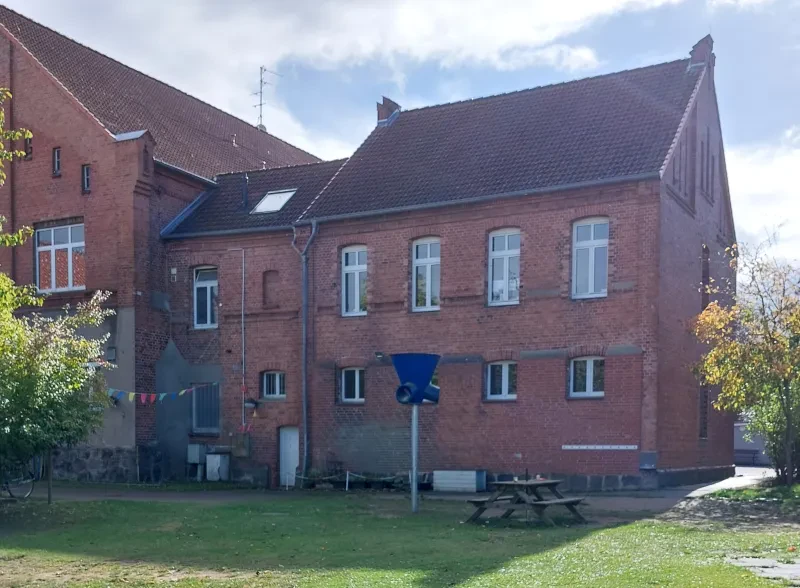 Ein roter Backsteinbau angebaut am Amtsgericht. Davor eine Bank.