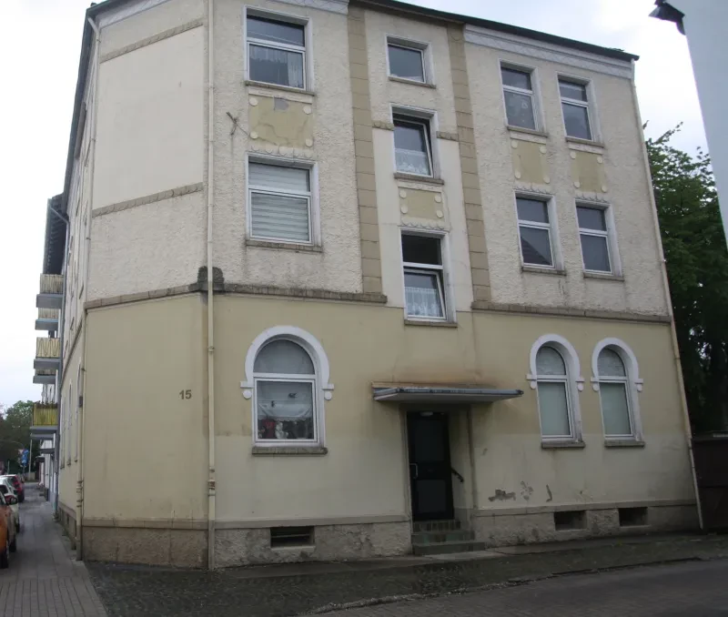 Ein dreistöckiges, hell verputztes, älteres Mehrfamilienhaus.