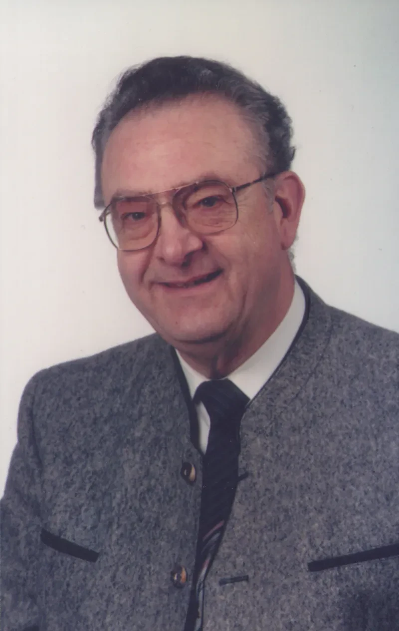 Ein älterer Herr mit Brille und einem Jacket im bayrischen Stil.