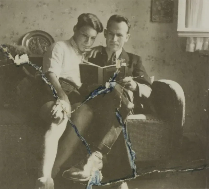 Ein Vater sitzt mit seinem Sohn auf einem Sofa. Beide schauen in ein Buch, sind im Lesen vertieft.