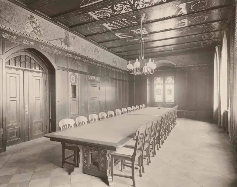 Ein Saal im Stettiner Polizeipräsidium, vor 1917. Zu sehen ist ein großer Tisch umringt von Stühlen in einem getäfelten Raum.