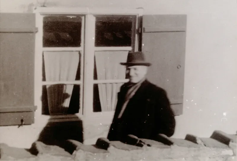 Ein Mann mit Hut vor einem Fenster.