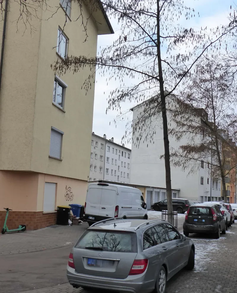 Blick in eine Straße mit mehrstöckigen Neubauten und parkenden Autos.