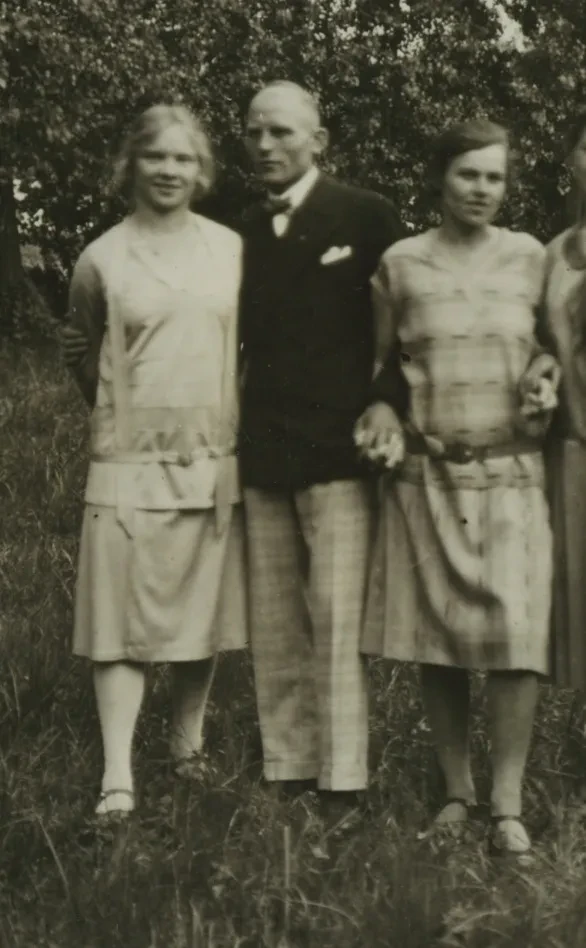 Ausschnitt aus einem Gruppenfoto: Ein Mann mit Fliege zwischen zwei Frauen.
