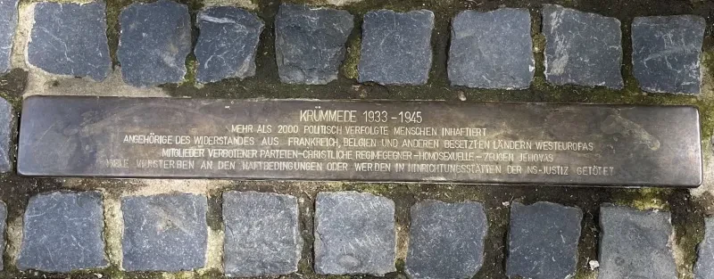 Stolperschwelle am Eingang der JVA Bochum: Text erinnert an mehr als 2000 politisch verfolgte Menschen 1933-1945, darunter Widerstandskämpfer aus Westeuropa, Mitglieder verbotener Parteien, christliche Regimegegner, Homosexuelle und Zeugen Jehovas; viele starben in Haft oder in NS-Hinrichtungsstätten.