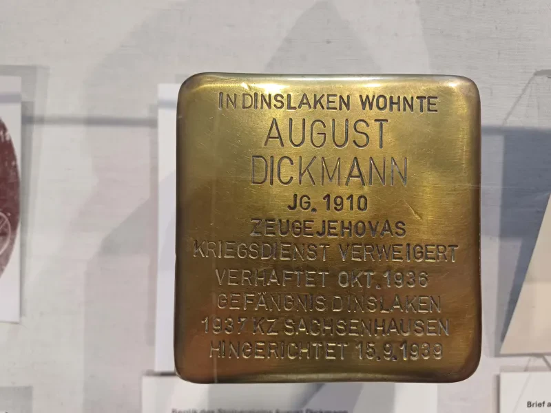 Ein Stolperstein mit der Aufschrift "In Dinslaken wohnte/August Dickmann/Jg. 1910/Zeuge Jehovas/Kriegsdienst verweigert/Verhaftet Okt. 1936/Gefängnis Dinslaken/1937 KZ Sachsenhausen/Hingerichtet 15.9.1939"