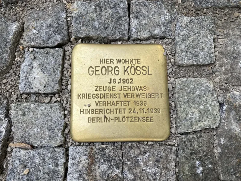 Stolperstein mit der Inschrift "Hier wohnte / Georg Kössl / Jg. 1902 / Zeuge Jehovas / Kriegsdienst verweigert / Verhaftet 1939 / Hingerichtet 24.11.1939 / Berlin-Plötzensee"