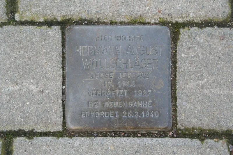 Ein Stolperstein mit der Inschrift: "Hier wohnte/Hermann August Wollschläger/Zeuge Jehovas/Jg. 1895/Verhaftet 1937/KZ Neuengamme/Ermordet 25.3.1940"