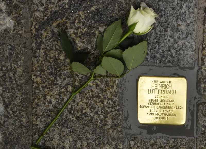 Ein Stolperstein mit der Aufschrift: "Hier wohnte / Heinrich Lutterbach / Jg. 1909 / Zeuge Jehovas / Verhaftet 1936 / Gefängnis Landsberg/Lech / 1937 Dachau / 1939 Mauthausen / Befreit"
