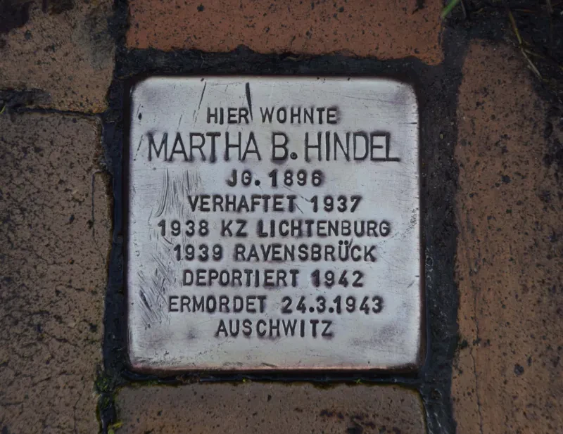 Ein Stolperstein mit der Inschrift: "Hier wohnte Martha B. Hindel / Jg. 1896 / Verhaftet 1896 / 1938 KZ Lichtenburg / 1939 Ravensbrück / Deportiert 1942 / Ermordet 24.3.1943 / Auschwitz"