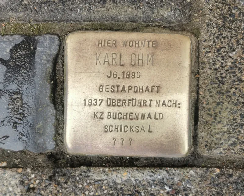 Ein Stolperstein trägt die Inschrift: "Hier wohnte Karl Ohm, Jahrgang 1890, Gestapohaft, 1987 überführt nach KZ Buchenwald, Schicksal ???".