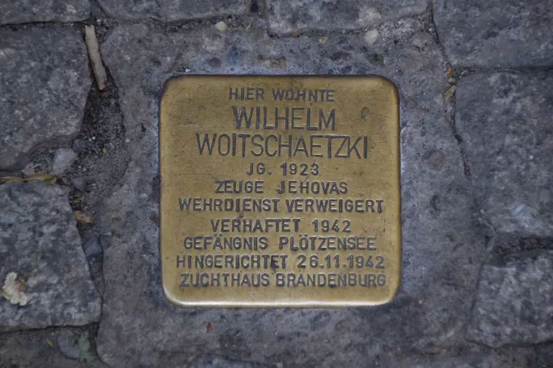 Ein Stolperstein mit der Aufschrift: "Hier wohnte / Wilhelm Woitschaetzki / Jg. 1923 / Zeuge Jehovas / Wehrdienst verweigert / Verhaftet 1942 / Gefängnis Plötzensee / Hingerichtet 26.11.1942 / Zuchthaus Brandenburg"