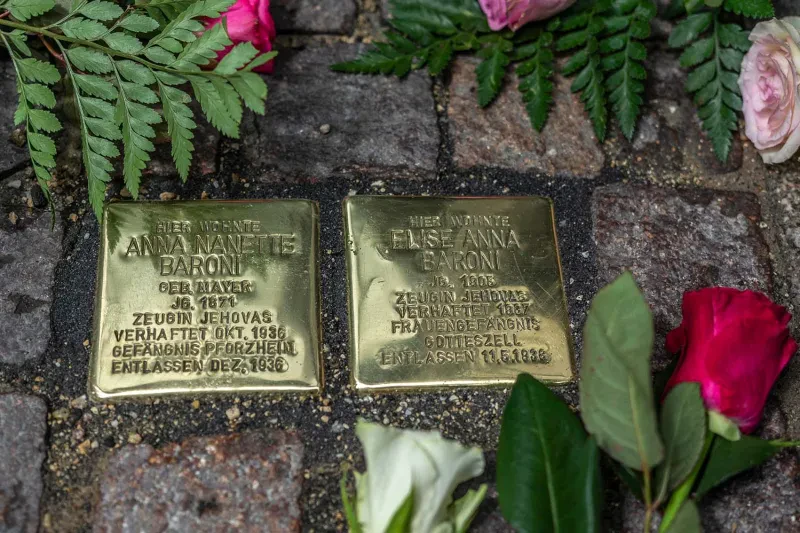 Zwei Stolpersteine für Anna und Elise Baroni, ringsum liegen Rosen.