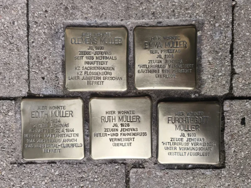 Fünf Stolpersteine auf einem Gehweg.