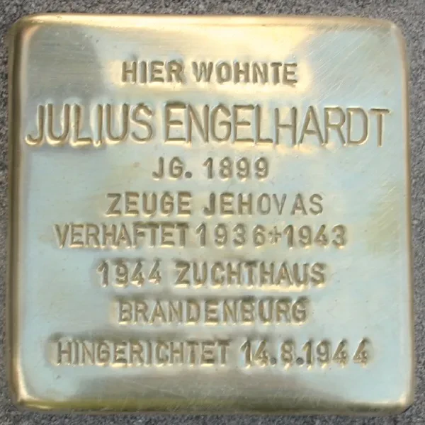 ein Stolperstein mit der Inschrift: „HIER WOHNTE JULIUS ENGELHARDT JG. 1899 ZEUGE JEHOVAS VERHAFTET 1936+1943 1944 ZUCHTHAUS BRANDENBURG HINGERICHTET 14.8.1944“