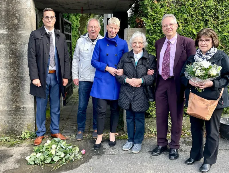 Rosen liegen auf dem Stolperstein von Karl Noske. Dahinter stehen 3 Männer und 3 Frauen.