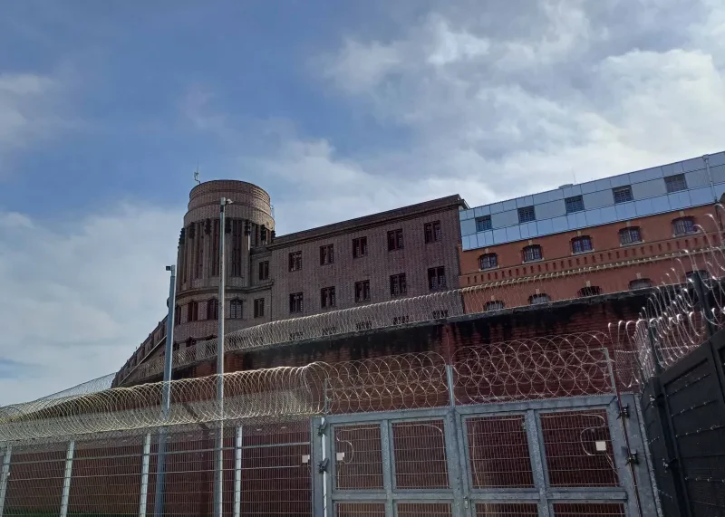 Das Hamburger Untersuchungsgefängnis am Holstenglacis, 2024. Blick von außen auf den Turm. Mauer mit Stacheldraht.