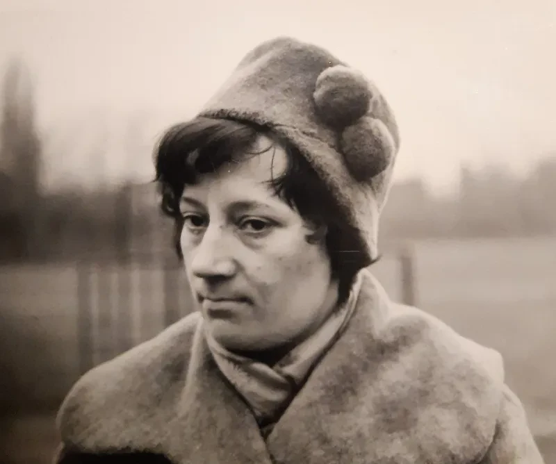 Portrait einer nachdenklich wirkenden Frau mit dickem Mantel, Hut und Schal.