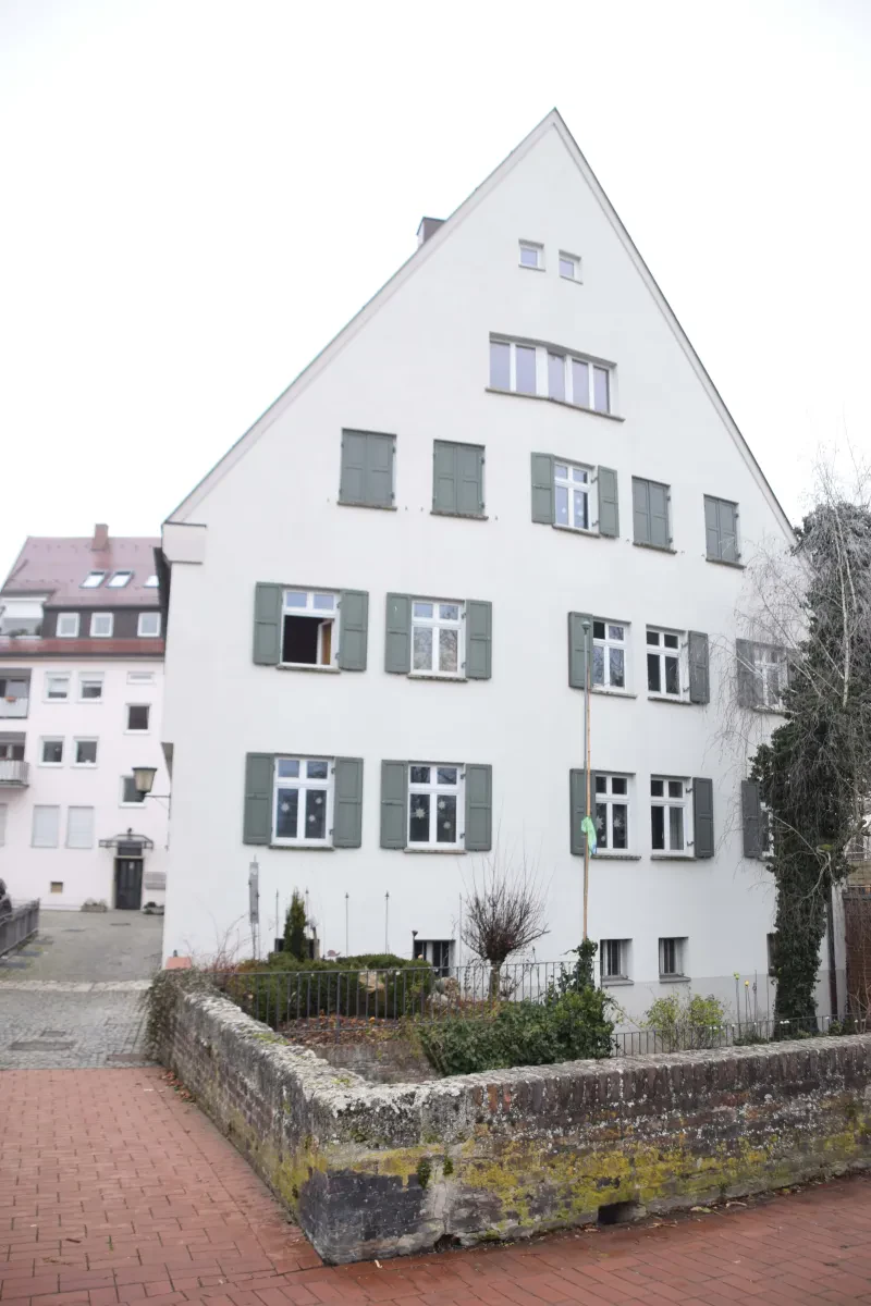 Ein weiß gestrichenes Haus hinter einer niedrigen Mauer.