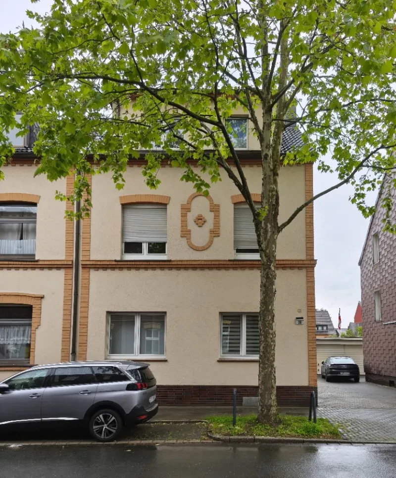 Ein Haus , davor ein baum und ein parkendes Auto.