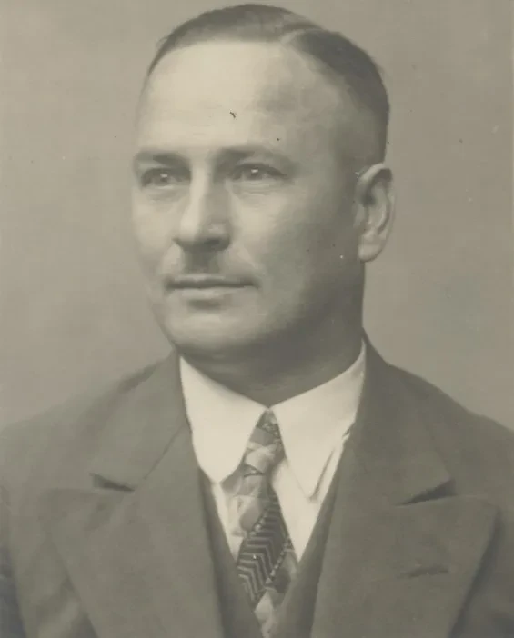 Portrait eines ca. 40jährigen Mannes im Anzug, der links an der Kamera vorbeisieht.