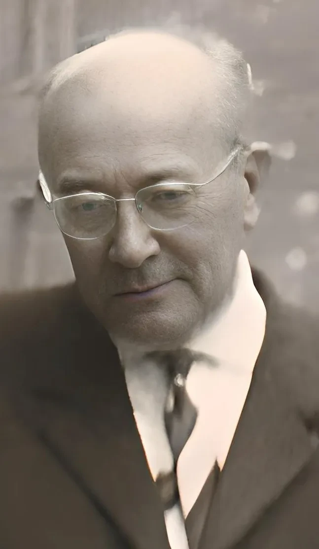 Ein Mann mit Brille und Krawatte blickt nach unten.
