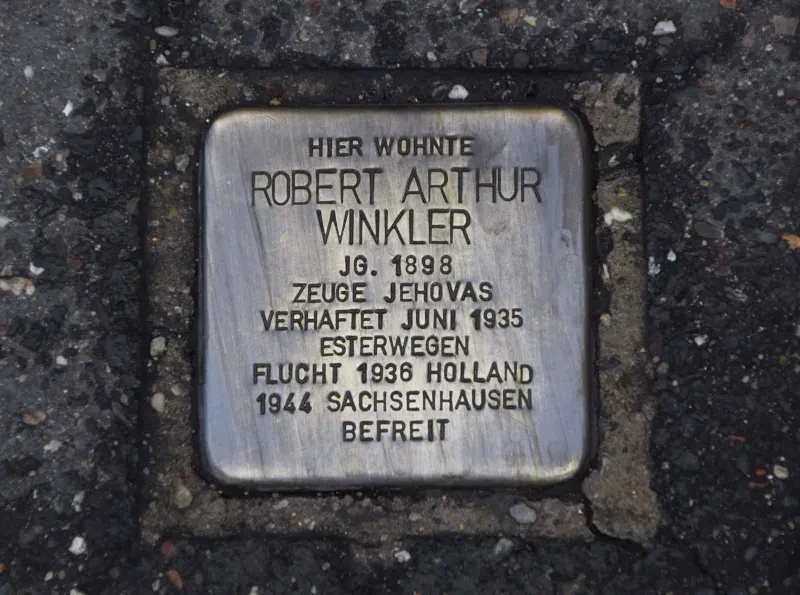 Ein Stolperstein mit der Inschrift: "Hier wohnte Robert Arthur Winkler/Jg.1898/Zeuge Jehovas/Verhaftet Juni 1935/Esterwegen/Flucht 1936 Holland/1944 Sachsenhausen/Befreit"