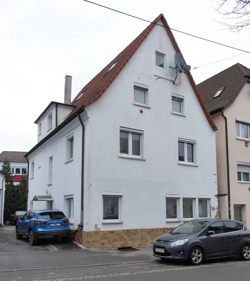 Ein Wohnhaus mit zwei davor parkenden Autos.