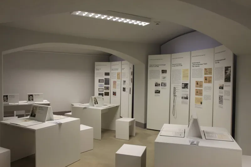 In einem Kellergewölbe finden sich Ausstellungstafeln und Ausstellungstische mit Lesemappen.